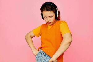 bonita menina dentro a laranja suéter fones de ouvido música entretenimento cortada Visão inalterado foto