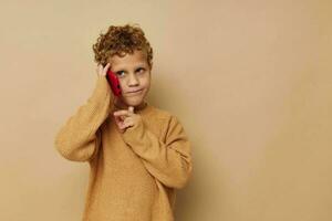 pequeno Garoto com encaracolado cabelo vermelho telefone tecnologia Diversão foto