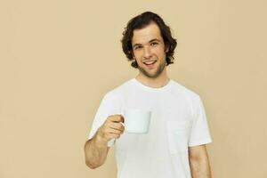 alegre homem dentro uma branco camiseta com uma caneca dentro mão estilo de vida inalterado foto