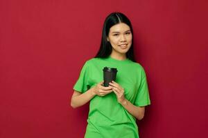 encantador jovem ásia mulher dentro uma verde camiseta uma vidro do beber Diversão estúdio modelo inalterado foto