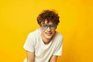 retrato do uma jovem encaracolado homem dentro uma branco camiseta azul moda óculos isolado fundo inalterado foto