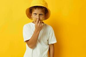 Garoto dentro branco camiseta amarelo chapéu posando emoções foto