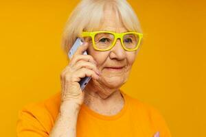 idosos mulher falando em a telefone dentro amarelo óculos isolado fundo foto