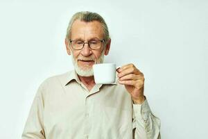 a idosos homem segurando uma caneca em uma branco fundo e sorridente foto