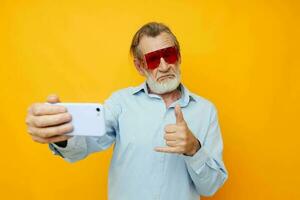 foto do aposentado velho homem azul camisas com óculos leva uma selfie isolado fundo