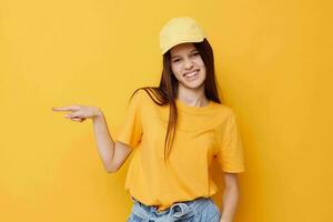 jovem lindo mulher posando dentro uma amarelo camiseta e boné amarelo fundo foto