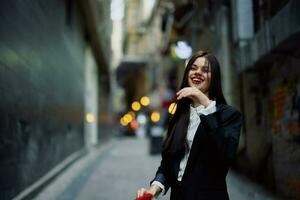 moda mulher sorrir com dentes e Diversão turista dentro à moda roupas dentro Jaqueta e vermelho boina caminhando baixa limitar cidade rua vôo cabelo, viagem, francês estilo, cinematográfico cor, retro estilo. foto