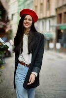 mulher sorrir moda modelo anda em em a rua dentro a cidade Centro entre a multidão dentro uma Jaqueta e vermelho boina e jeans, cinematográfico francês moda estilo roupas, viagem para Istambul Primavera foto