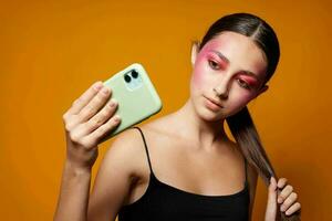 elegante mulher brilhante Maquiagem posando Preto jérsei com uma telefone dentro mão isolado fundo inalterado foto