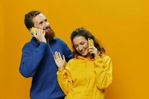 homem e mulher casal sorridente alegremente com telefone dentro mão social meios de comunicação vendo fotos e vídeos, em amarelo fundo, símbolos sinais e mão gestos, família freelancers.