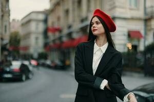 moda mulher retrato em pé em a rua dentro frente do a cidade dentro à moda roupas com vermelho lábios e vermelho boina, viagem, cinematográfico cor, retro vintage estilo, urbano moda estilo de vida. foto