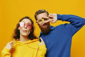 homem e mulher casal sorridente alegremente e torto com copos, em amarelo fundo, símbolos sinais e mão gestos, família atirar, recém-casados. foto