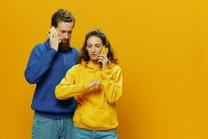 homem e mulher casal sorridente alegremente com telefone dentro mão social meios de comunicação vendo fotos e vídeos, em amarelo fundo, símbolos sinais e mão gestos, família freelancers.