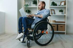 homem cadeira de rodas trabalhador autonomo trabalhando às computador portátil às casa sorriso, trabalhando on-line, social redes e comece, cópia de espaço, integração para dentro sociedade, saúde conceito homem com deficiências, real pessoa fechar-se foto