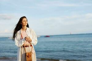 freelance mulher com telefone dentro mão em período de férias caminhando em a de praia de a oceano dentro Bali, feliz viagem e férias, Móvel comunicações, Internet conectados foto