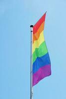 vertical arco Iris ou lgbtq orgulho bandeira em mastro de bandeira foto