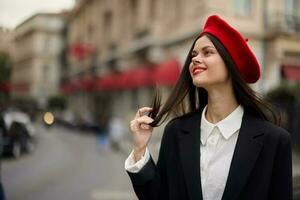 moda mulher retrato sorrir dentes em pé em a rua dentro a cidade fundo dentro à moda roupas com vermelho lábios e vermelho boina, viagem, cinematográfico cor, retro vintage estilo, urbano moda estilo de vida. foto