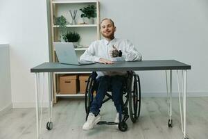 homem dentro cadeira de rodas homem de negocios dentro escritório às computador portátil, sorrir e felicidade, polegares acima, conceito do trabalhos Desativado pessoa, liberdade a partir de social quadros foto