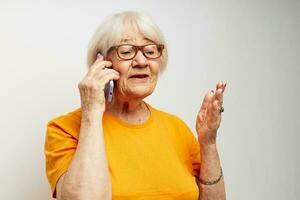 retrato do a velho amigáveis mulher dentro casual camiseta oculos de sol falando em a telefone cortada Visão foto