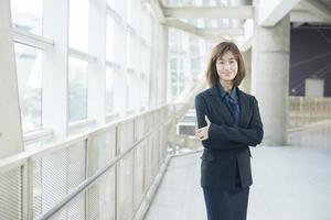 Mulher de negócios asiática atraente sorrindo fora do escritório foto