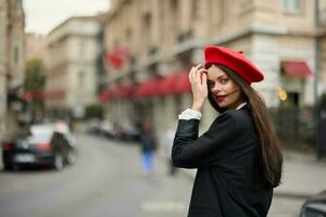 moda mulher retrato sorrir dentes em pé em a rua dentro a cidade fundo dentro à moda roupas com vermelho lábios e vermelho boina, viagem, cinematográfico cor, retro vintage estilo, urbano moda estilo de vida. foto