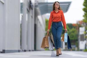 retrato ao ar livre de uma mulher feliz segurando sacolas de compras foto