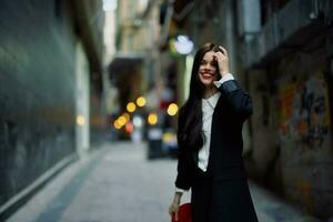 moda mulher sorrir com dentes e Diversão turista dentro à moda roupas dentro Jaqueta e vermelho boina caminhando baixa limitar cidade rua vôo cabelo, viagem, francês estilo, cinematográfico cor, retro estilo. foto