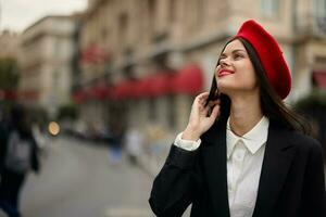 moda mulher retrato sorrir dentes em pé em a rua dentro a cidade fundo dentro à moda roupas com vermelho lábios e vermelho boina, viagem, cinematográfico cor, retro vintage estilo, urbano moda estilo de vida. foto