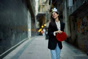 moda mulher sorrir com dentes e Diversão turista dentro à moda roupas dentro Jaqueta e vermelho boina caminhando baixa limitar cidade rua vôo cabelo, viagem, francês estilo, cinematográfico cor, retro estilo. foto