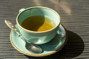 inacabado turquesa copo do chá em uma mesa dentro uma cafeteria dentro a luz solar foto