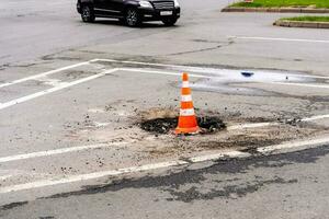 sinal tráfego cone em uma defeituoso esgoto bueiro em uma cidade rodovia foto