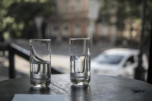 dois copos de água ficam sobre a mesa de um restaurante no fundo das ruas da cidade foto