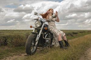 garota ruiva em um vestido branco e botas junto com um campo de lavanda de motocicleta foto