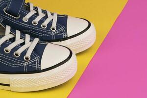 uma par do azul tênis em uma amarelo-rosa fundo foto