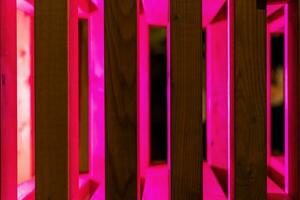 abstrato fundo do de madeira ripas iluminado com vermelho néon luz foto