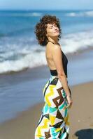 sereno fêmea turista em pé contra mar em ensolarado dia foto