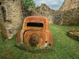 velho oxidado carros esquerda atrás dentro oradour-sur-gllane, França. foto