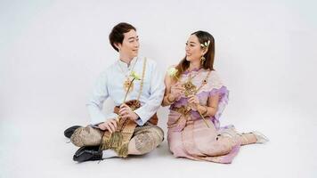 ásia casal dentro tradicional tailandês traje segurando lótus e olhando às cada de outros isolado em branco fundo, Tailândia tradicional cultura foto