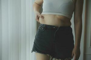 mulher gorda, barriga gorda, gordinha, mão de mulher obesa segurando gordura excessiva da barriga com fita métrica, conceito de estilo de vida de dieta de mulher foto