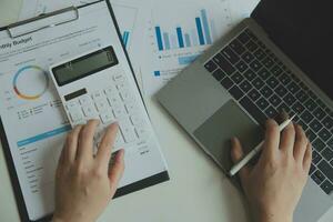 mulher empreendedora usando uma calculadora com uma caneta na mão, calculando despesas financeiras em home office foto