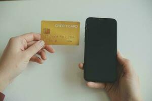 mãos de mulher segurando e usando cartão de crédito para compras online. foto