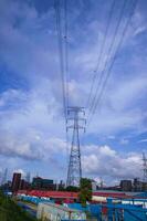 Alto Voltagem eletricidade pilone com paisagem urbana e azul céu fundo. foto