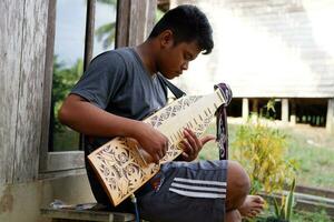 kuaro Kalimantan timur, Indonésia 21 Junho 2023. uma homem jogando uma tradicional Kalimantan dayak musical instrumento foto