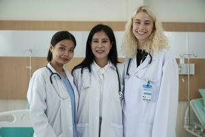 profissional médico funcionários equipe, três branco uniformizado fêmea médicos olhando às Câmera, alegre e sorridente, feliz fisica trabalhos ocupação dentro hospital clínica. foto