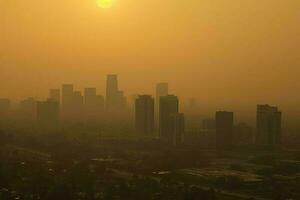 ai gerado Sol lutas para penetrar a poluição, fundição uma doentio amarelo brilho sobre tudo. foto