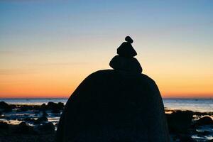 pedra pirâmide em a báltico mar com uma Visão do a mar às pôr do sol e azul hora foto