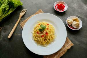 aglio e olio. italiano massa espaguete, aglio olio e calabresa ,espaguete com alhos, Oliva óleo e Pimenta pimentas em prato em mesa foto