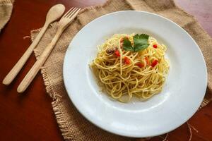 aglio e olio. italiano massa espaguete, aglio olio e calabresa ,espaguete com alhos, Oliva óleo e Pimenta pimentas em prato em mesa foto