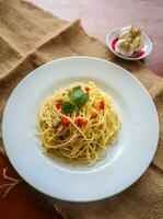 aglio e olio. italiano massa espaguete, aglio olio e calabresa ,espaguete com alhos, Oliva óleo e Pimenta pimentas em prato em mesa foto