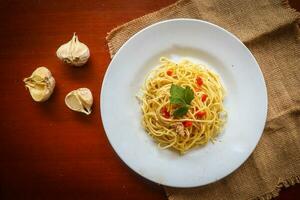 aglio e olio. italiano massa espaguete, aglio olio e calabresa ,espaguete com alhos, Oliva óleo e Pimenta pimentas em prato em mesa foto